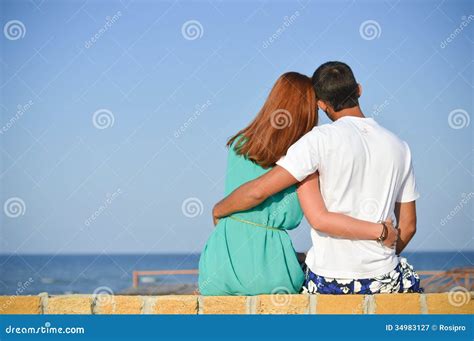 Romantic Happy Couple Looking At Sea Sitting On Sandy Beach And