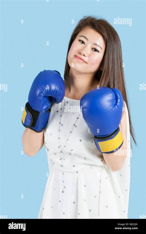 Portrait Of A Beautiful Young Woman Wearing Boxing Gloves Over Blue