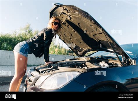 Picture Of Side Of Woman Standing In Front Of Black Car With Open Hood