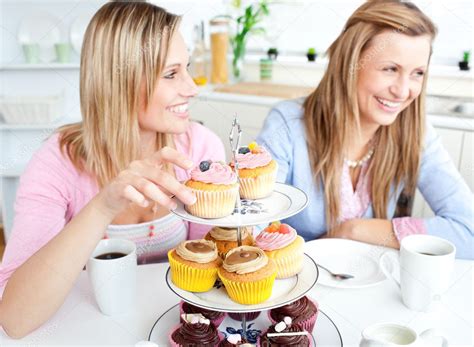 Women Having Fun Eating Cupcakes In The Kitchen Stock Photo Wavebreakmedia