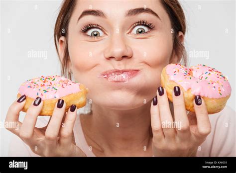 Close Up Portrait Of A Satisfied Pretty Girl Eating Donuts Isolated Over White Background Stock