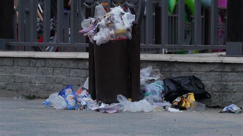 Trash Spilling Out Of Overfilled Trash Plastic Bag On City Street