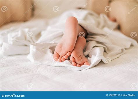 Feet Of Little Sleeping Child Under White Blanket On The Bed Stock