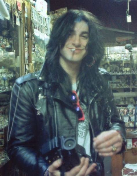 A Man With Long Hair Wearing A Leather Jacket And Holding A Camera In