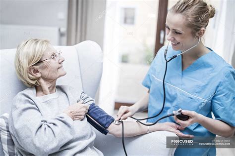 Female Nurse Taking Blood Pressure Of Senior Woman — Assistance