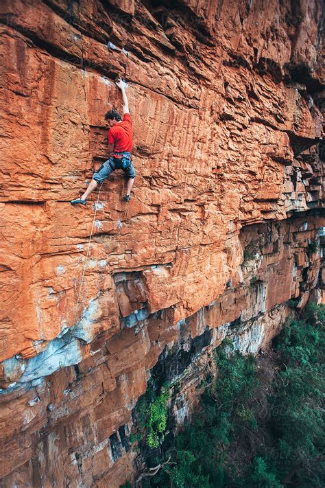 Fit Rock Climber Climbing An Extreme Cliff Face In A Mountain By