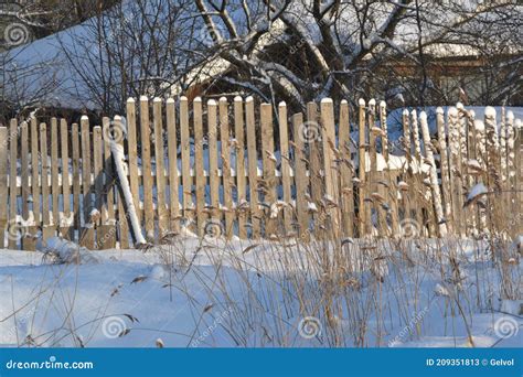 Wooden Fence With A Locked Door Among Snowdrifts And White Snow Near A