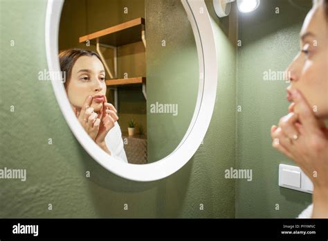 Woman In Bathrobe Making Facial Massage Looking Into The Round Mirror In The Bathroom Stock