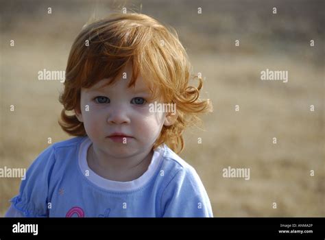 Head And Shoulders Of A Red Headed Blue Eyed Baby Girl With A Serious