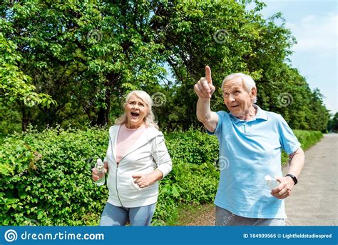 Senior Man Pointing With Finger Near Wife Holding Bottle In Park Stock Image Image Of Daylight