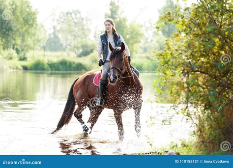 Young Teenage Girl Riding Horseback In River At Early Morning Stock