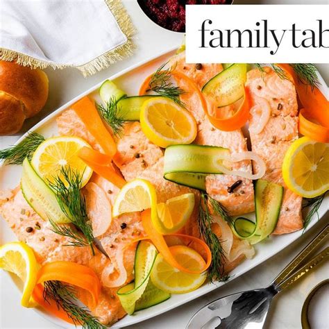 A Plate With Salmon Cucumbers And Lemons On It Next To Silverware