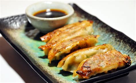 Gyoza are a dumpling commonly prepared in east asia. tsukurikata: pork gyoza (potstickers) with dipping sauce