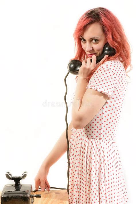 Redhead Woman With A Retro Look Speaking At A Vintage Phone Stock Photo