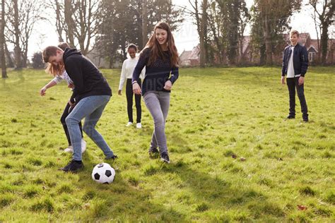 Group of teenagers playing soccer in park together - Stock Photo - Dissolve