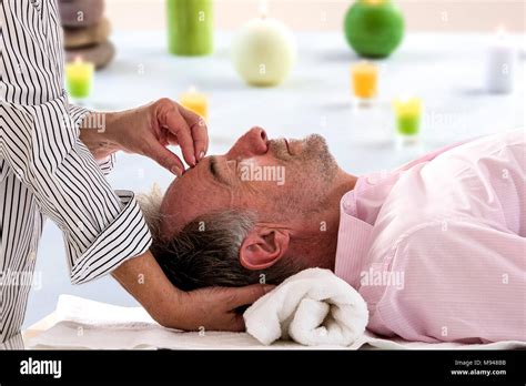 Side View Of Relaxed Senior Man Receiving Forehead Massage In Spa Beaty