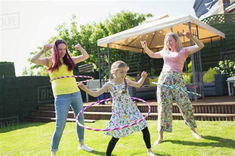 Lesbian Couple And Daughter Playing With Plastic Hoops In Sunny