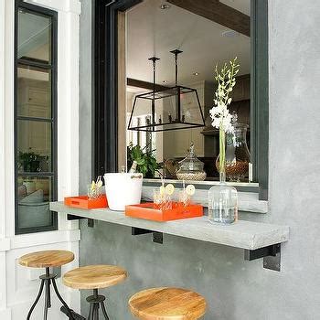 A pass through is located above a farmhouse sink matched with a polished nickel gooseneck faucet fixed to a white quartz countertop accenting light gray shaker cabinets finished with brass hardware. Kitchen Pass Through Design Ideas