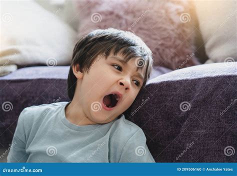 Authentic Tired Kid Yawning Sitting Next To Sofasleepy Boy Yawning And
