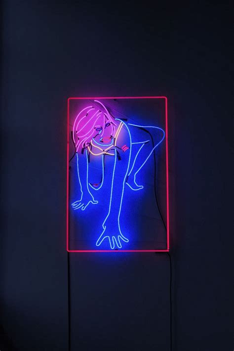 A Neon Sign With A Woman Bending Over It S Head In The Middle Of A Dark Room
