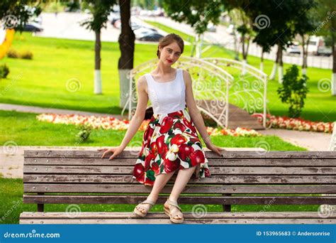Beautiful Girl In Summer Dress Sitting On A Park Bench Stock Image