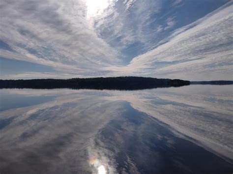 The Sky Is Reflected In The Still Water On The Lakes Surface While