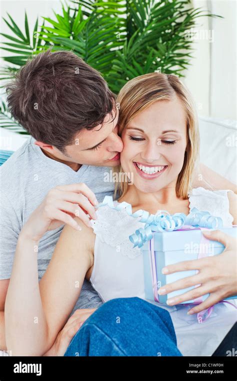 Attentive Man Kissing Her Girlfriend After Giving Her A Present Both