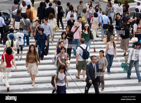 Japanese People Walking Across A Busy Street At A Crosswalk In Tokyo