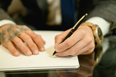 Person Holding Black Pen Writing On White Paper · Free Stock Photo