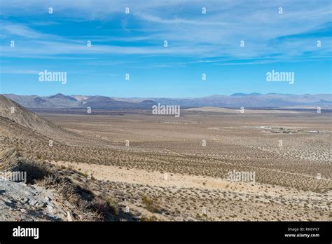 Looking Out Across A Valley In The Mojave Desert With Sparse Vegetation