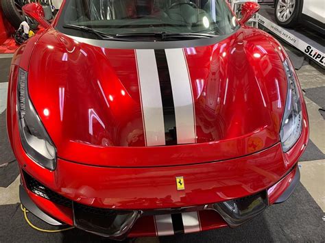A Red Sports Car With White Stripes On Its Hood Is Parked In A Garage