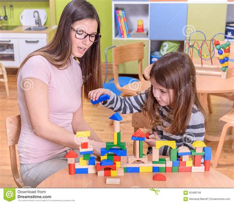 Preschool Teacher Helps Cute Girl To Build Toy Castle