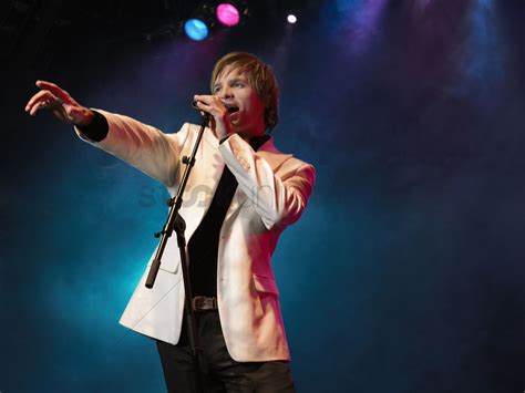 Young Man Singing Into Microphone On Stage At Concert Low Angle View