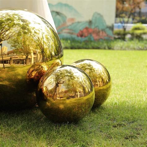 Three Shiny Balls Sitting In The Grass Near Each Other