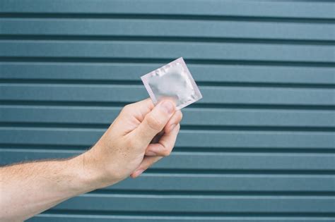 Premium Photo A Picture Of Mans Hand Holding Packed Condom Isolated
