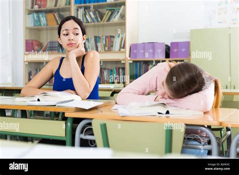 Portrait Schoolgirl And Her Girlfriend Who Is Sleeping On The Desk In