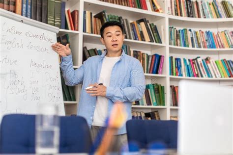Chinese Teacher Pointing At Whiteboard Having Online Class In Classroom