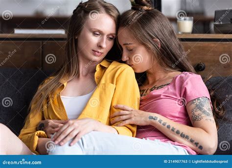 two pretty lesbians embracing while sitting on sofa in living room stock image image of