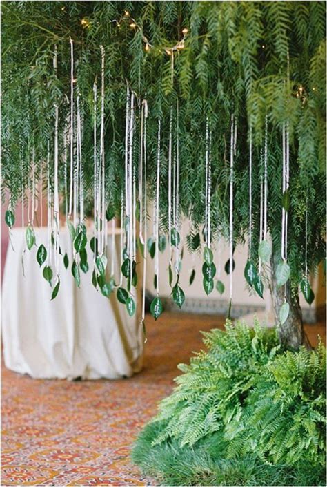 The Table Is Set Up With White Linens And Greenery Hanging From The Trees