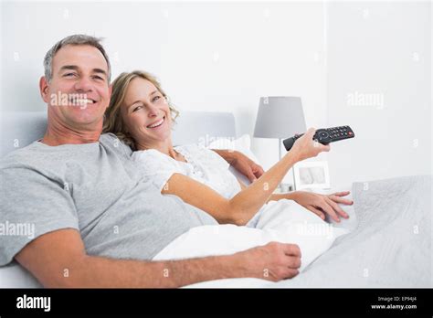Happy Couple Cuddling In Bed Watching Television Stock Photo Alamy