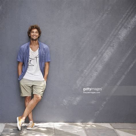 Full Length Shot Of A Handsome Young Man Leaning Against A Gray Wall