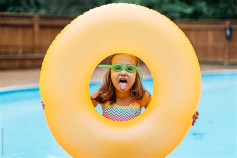 Cute Young Girl Playing With Her Inner Tube By A Pool By Stocksy