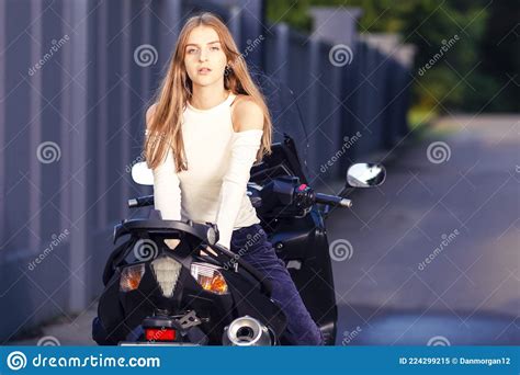 sensual caucasian female motorcyclist biker leaning on sport bike outdoor while sitting back to