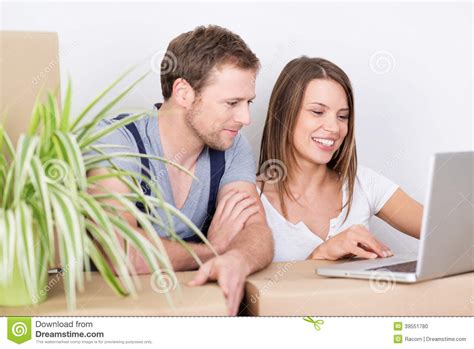 casa commovente delle giovani coppie che esamina un computer portatile fotografia stock