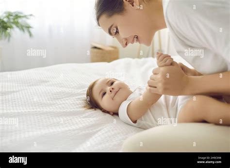 Happy Young Mother And Her Funny Adorable Baby Are Playing And