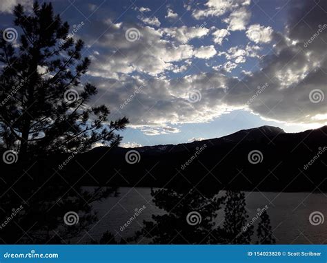 Dark Clouds Threaten Rain Over A Lake And Valley Of Pine Stock Photo