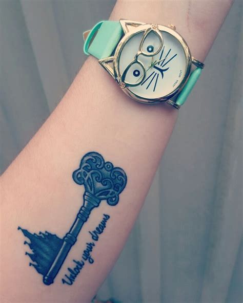A Womans Arm With A Wrist Tattoo And A Watch On It That Has A Key