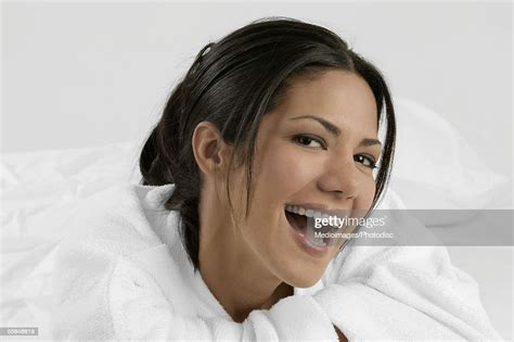 Portrait Of Smiling Young Woman Wearing Bathrobe And Lying On Stomach
