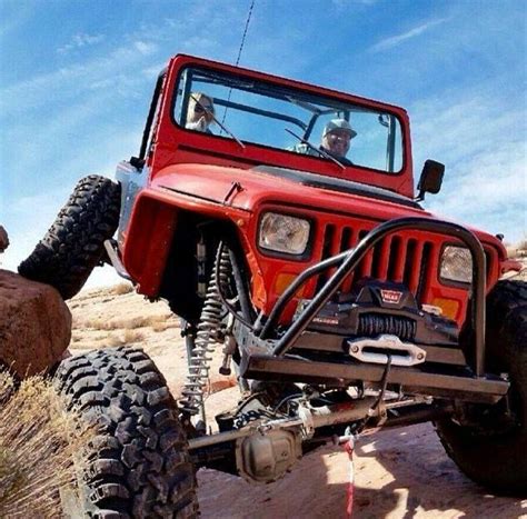 A Red Jeep Driving Down A Dirt Road