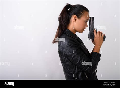 Profile View Of Young Asian Woman Holding Handgun Against White Stock